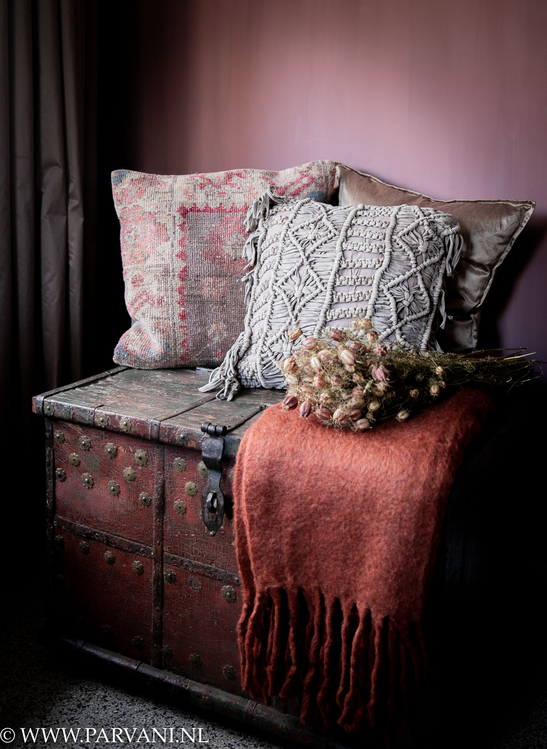 stoeprand Kaal Vakman Sierkussens en plaid in warme rood oranje oud roze kleur met taupe naturel  kleuren op oude rode houten kist | Parvani