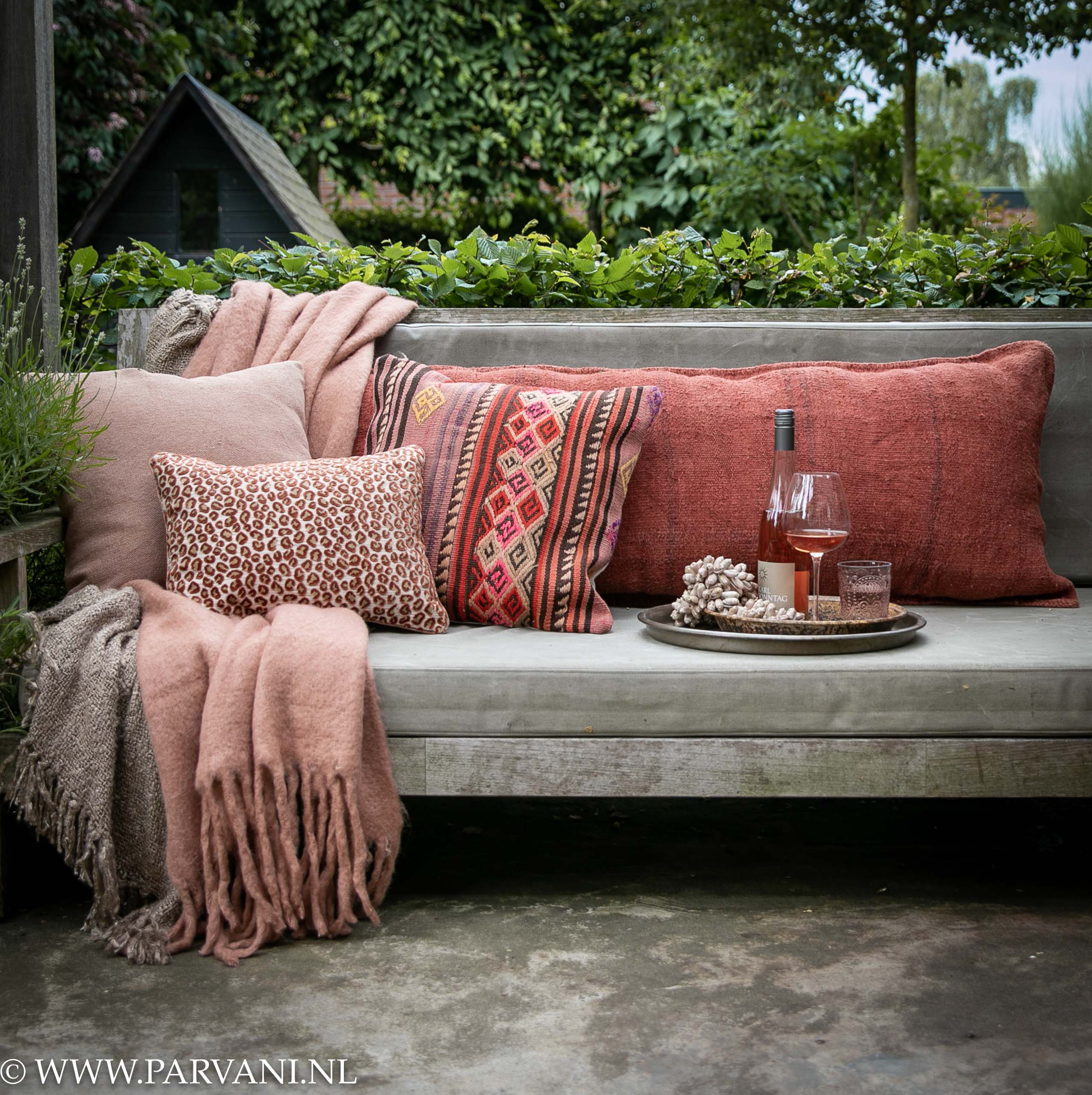 kapok katoen Amerika Tuinbank met plaids en linnen, hennep en kelim kussens in rood roze tinten  | Parvani